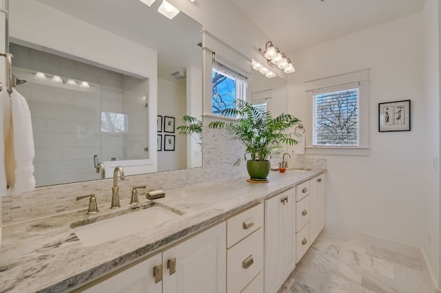 bathroom featuring backsplash, marble finish floor, a stall shower, and a sink