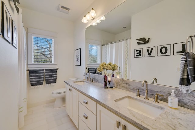 bathroom featuring a sink, visible vents, toilet, and double vanity