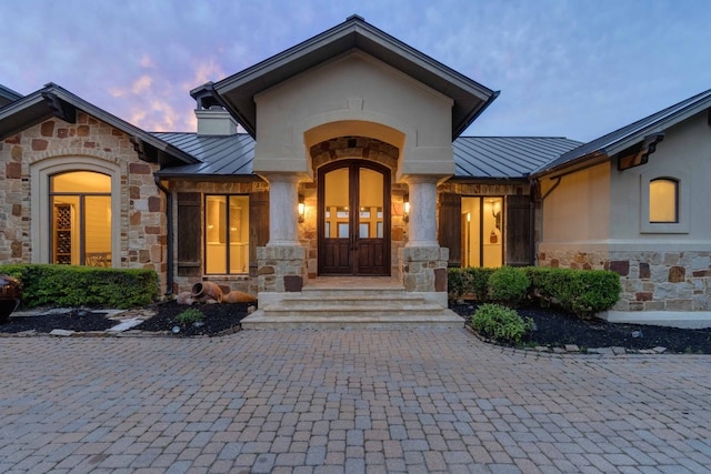 9104 Atwater Cv, Austin, TX 78733 - exterior entry at dusk with a standing seam roof, stone siding, and metal roof