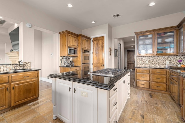 9104 Atwater Cv, Austin, TX 78733 - kitchen with appliances with stainless steel finishes, decorative backsplash, glass insert cabinets, recessed lighting, and a center island