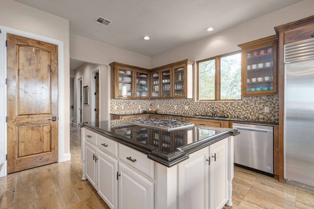9104 Atwater Cv, Austin, TX 78733 - kitchen featuring appliances with stainless steel finishes, backsplash, a sink, glass insert cabinets, and recessed lighting