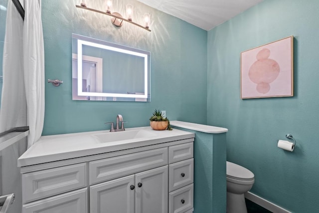 bathroom featuring baseboards, toilet, and vanity