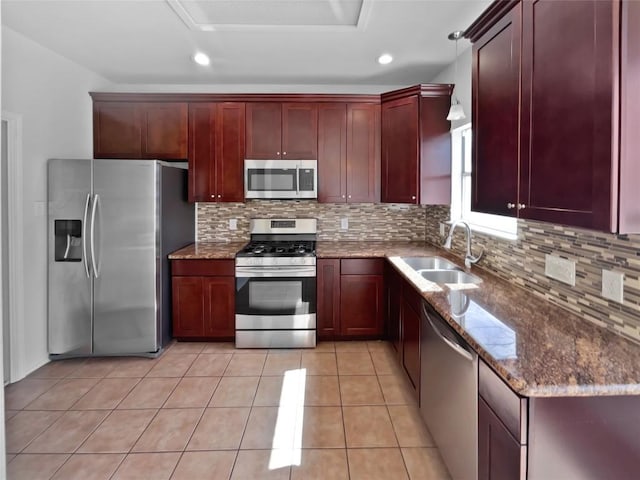 13449 Gent Dr, Austin, TX 78729 - kitchen featuring stainless steel appliances, reddish brown cabinets, a sink, backsplash, and dark stone counters
