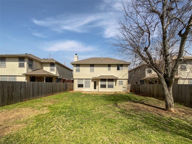 back of property with a yard, a fenced backyard, a chimney, and stucco siding