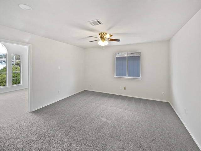 carpeted spare room with visible vents, baseboards, and ceiling fan