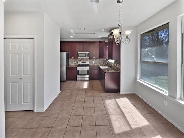 kitchen featuring light tile patterned floors, a sink, decorative backsplash, stainless steel appliances, and decorative light fixtures