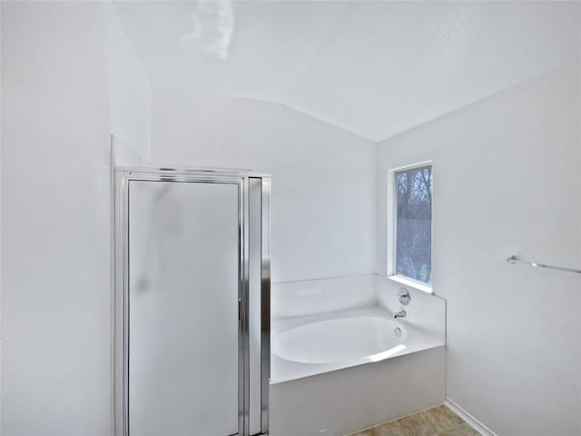 bathroom featuring lofted ceiling, a bath, and a stall shower