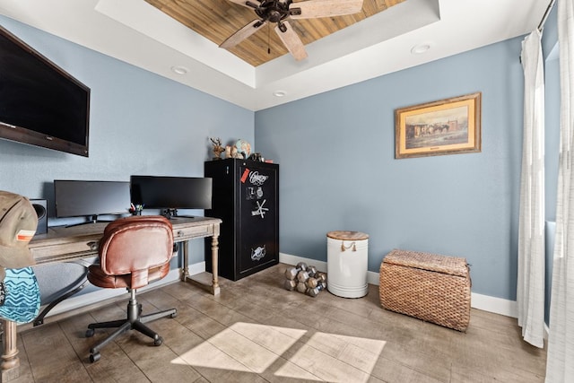 office space featuring a ceiling fan, a tray ceiling, wood ceiling, and baseboards