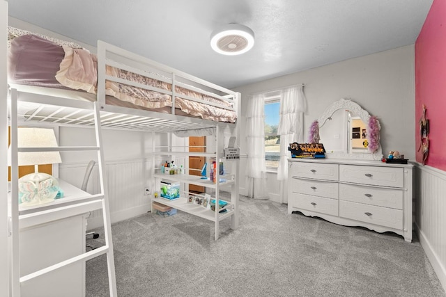 bedroom with light carpet and a wainscoted wall