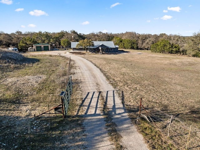 view of street with a rural view and dirt driveway