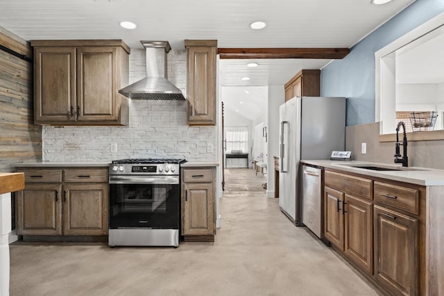 kitchen with finished concrete flooring, a sink, stainless steel appliances, wall chimney exhaust hood, and backsplash