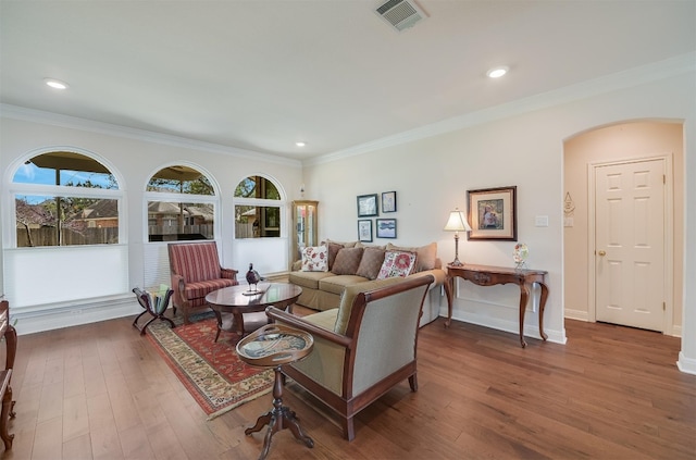 living area featuring visible vents, ornamental molding, wood finished floors, arched walkways, and baseboards