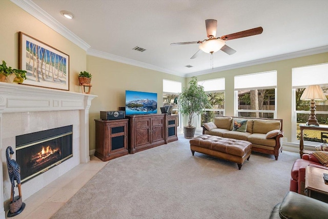 living room featuring visible vents, ornamental molding, light colored carpet, ceiling fan, and a tile fireplace