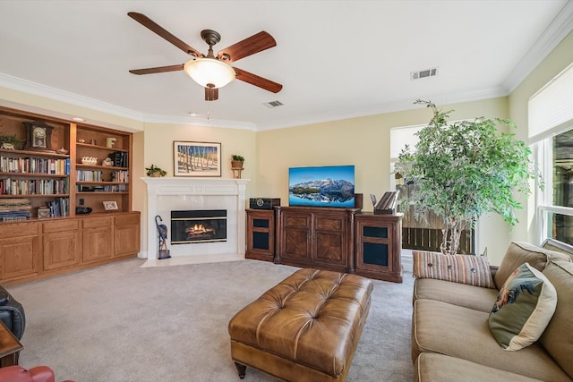 carpeted living room with visible vents, ornamental molding, a ceiling fan, and a tile fireplace