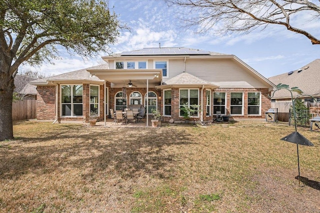 rear view of property featuring a patio, a ceiling fan, a fenced backyard, a lawn, and brick siding