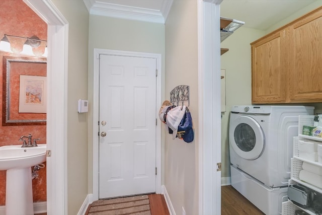 laundry area with wood finished floors, washer / dryer, cabinet space, a sink, and ornamental molding