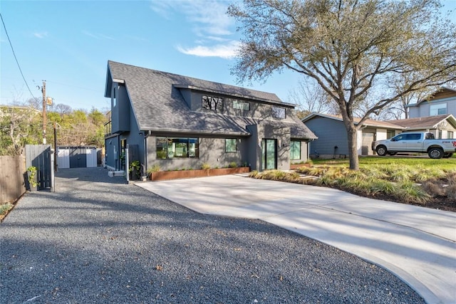 view of front of house with stucco siding, driveway, a gate, fence, and a shingled roof