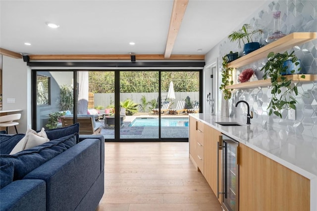 kitchen featuring open shelves, beverage cooler, light wood-style flooring, modern cabinets, and a sink