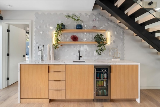 bar with light wood finished floors, wet bar, a sink, wine cooler, and tasteful backsplash