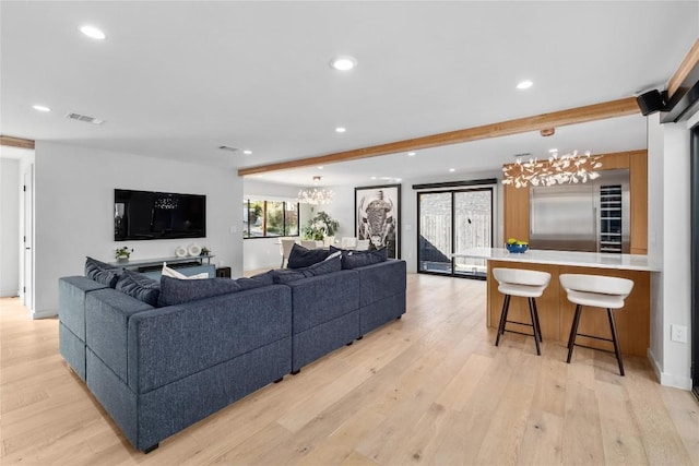 living area with recessed lighting, visible vents, beamed ceiling, and light wood finished floors