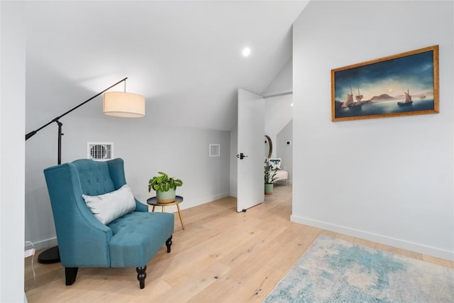 sitting room with lofted ceiling, wood finished floors, visible vents, and baseboards