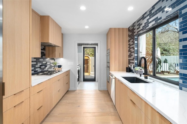 kitchen with light brown cabinetry, modern cabinets, and a sink