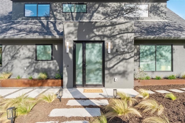 property entrance with stucco siding and a shingled roof