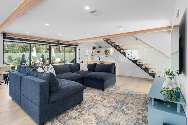 living area with stairs, beamed ceiling, wood finished floors, and visible vents