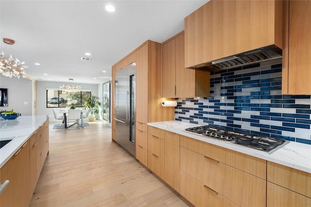 kitchen featuring visible vents, light stone countertops, light wood-type flooring, stainless steel gas stovetop, and a notable chandelier