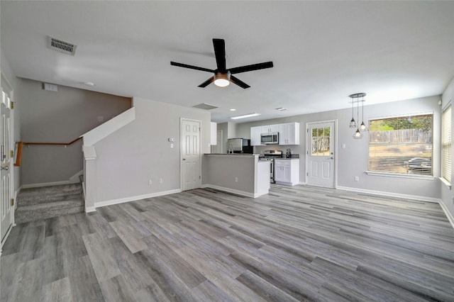 unfurnished living room with visible vents, ceiling fan, baseboards, light wood-type flooring, and stairs