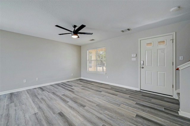 unfurnished room with visible vents, a ceiling fan, a textured ceiling, wood finished floors, and baseboards