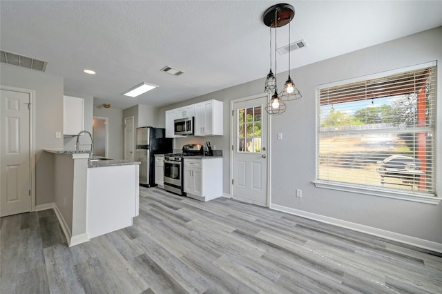 kitchen featuring visible vents, appliances with stainless steel finishes, white cabinetry, and a peninsula