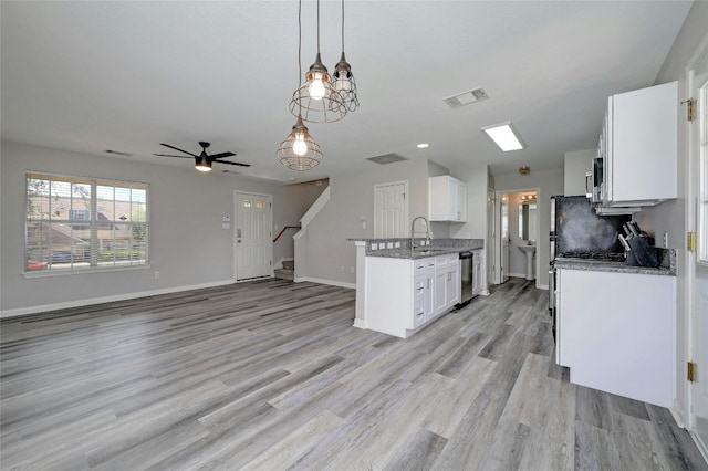 kitchen with visible vents, light wood-style flooring, open floor plan, white cabinetry, and stainless steel appliances