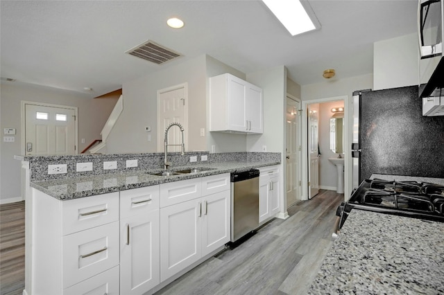 kitchen featuring visible vents, a peninsula, a sink, black appliances, and white cabinets