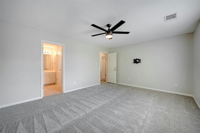 unfurnished bedroom featuring baseboards, visible vents, ceiling fan, ensuite bathroom, and carpet flooring