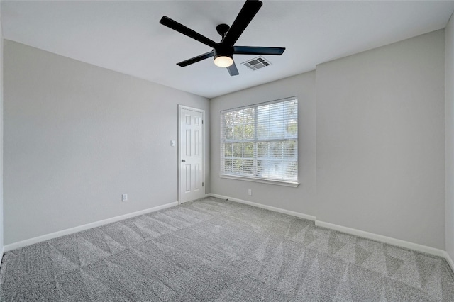 carpeted empty room featuring baseboards, visible vents, and ceiling fan