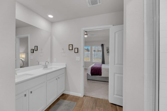 full bathroom with connected bathroom, wood finished floors, visible vents, and a sink