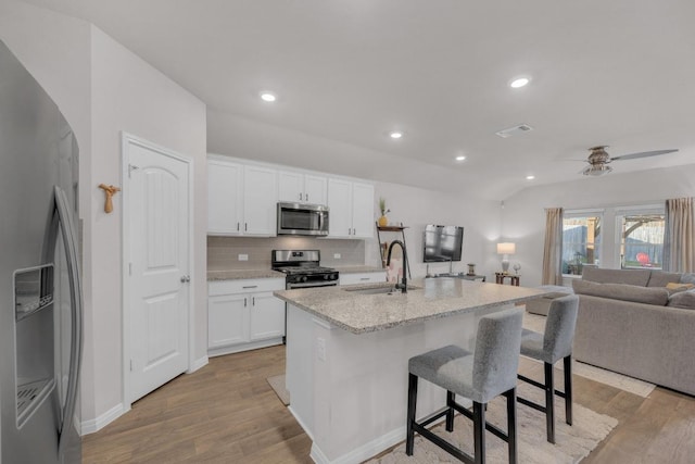 kitchen with open floor plan, stainless steel appliances, light wood-type flooring, and a sink