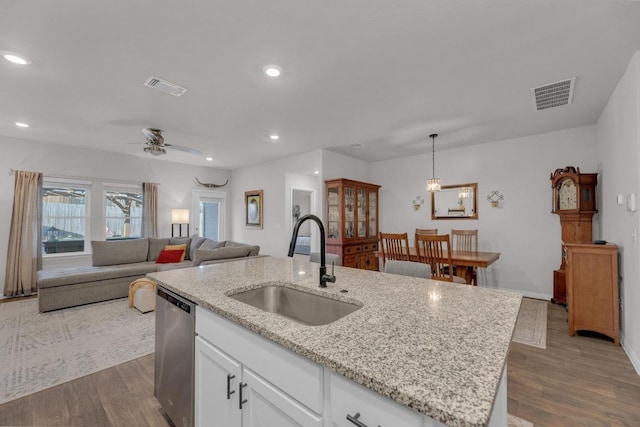 kitchen featuring a sink, visible vents, stainless steel dishwasher, and dark wood finished floors