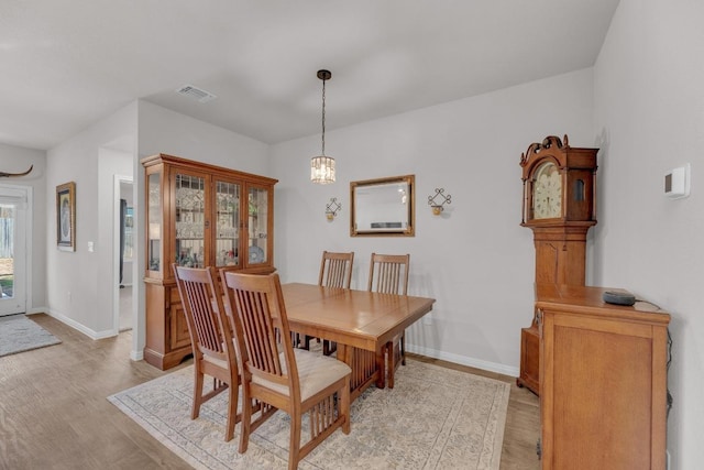 dining area featuring light wood-type flooring, visible vents, and baseboards