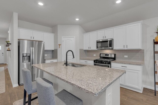 19425 Abigail Fillmore Rd, Manor, TX 78653 - kitchen featuring stainless steel appliances, a sink, wood finished floors, white cabinetry, and recessed lighting