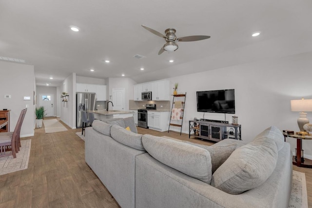 living room with a ceiling fan, recessed lighting, baseboards, and light wood finished floors