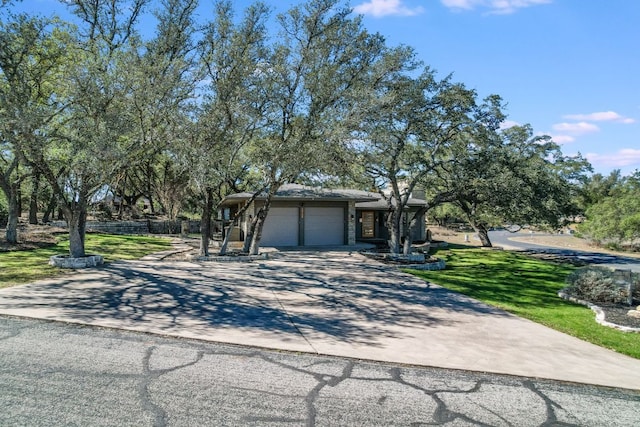 view of front facade with a front lawn, concrete driveway, an attached garage, and fence