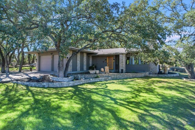 view of front of house featuring a front lawn, an attached garage, brick siding, and driveway