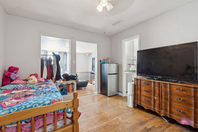 bedroom with visible vents, light wood-style flooring, freestanding refrigerator, a closet, and a spacious closet