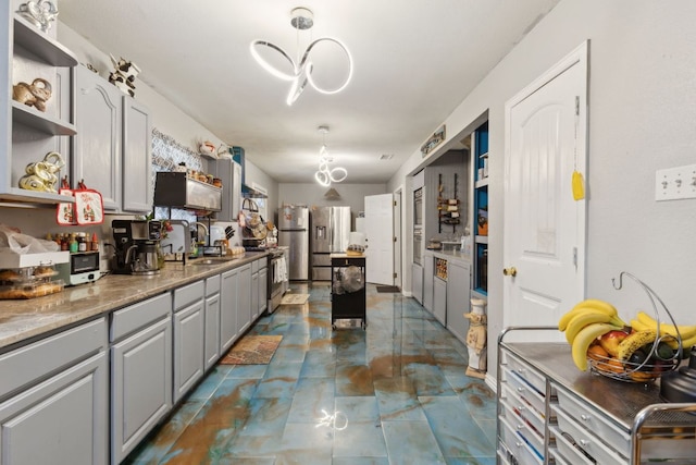 kitchen featuring gray cabinetry, open shelves, a sink, freestanding refrigerator, and an inviting chandelier