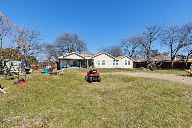 rear view of property featuring a lawn and a fenced backyard