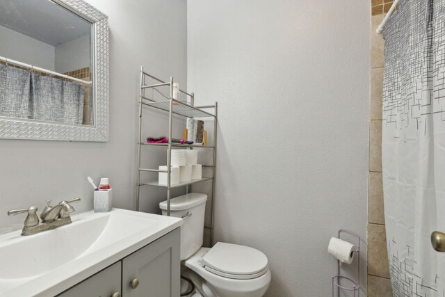 full bath with toilet, vanity, and a shower with curtain