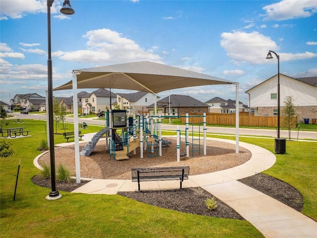 communal playground with fence, a lawn, and a residential view