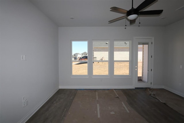 empty room featuring a ceiling fan, baseboards, and wood finished floors